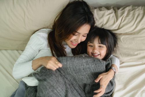 family happy time with mom and daughter play together on morning bed